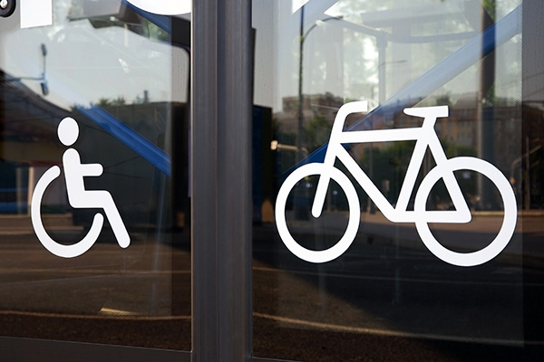 Large white signs of disabled person and bicycle on glass bus doors, close-up