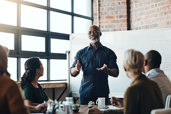 person in front of white board teaching a group of people