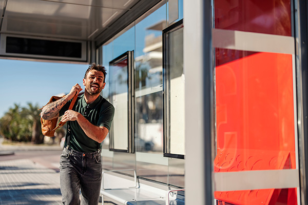 A man at a bus shelter runs to catch the bus