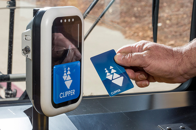 A man holds a clipper card while getting on the bus.