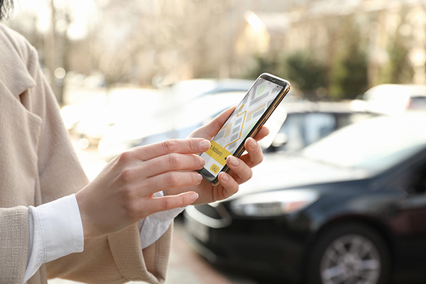 Woman ordering taxi with smartphone on city street