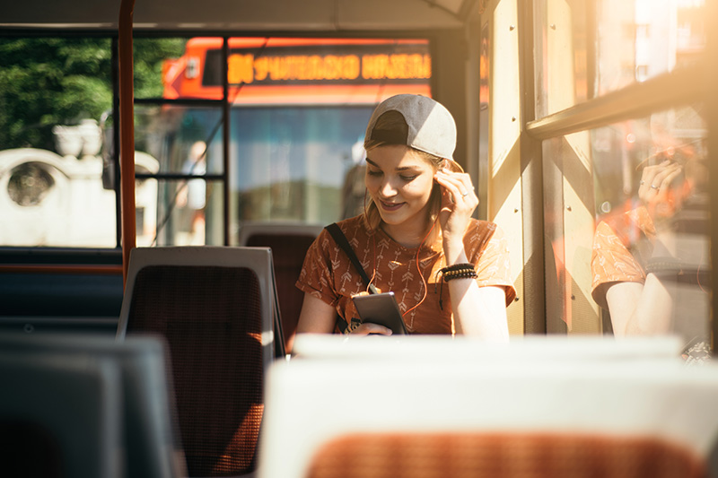 A teenager on the bus listening to ear buds