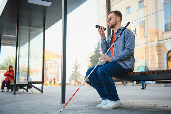 A blind person at a bus shelter on the phone