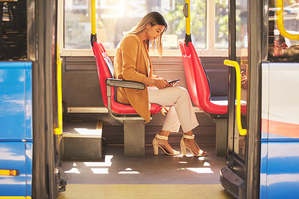 Woman in bus, typing on her smartphone during commute.