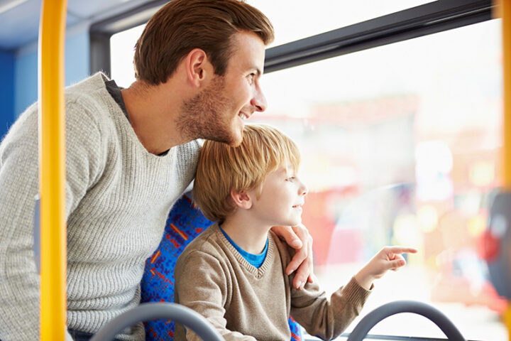 A man and his son look out of the bus window smiling