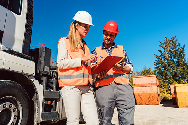 Two people wearing hard hats signing papers