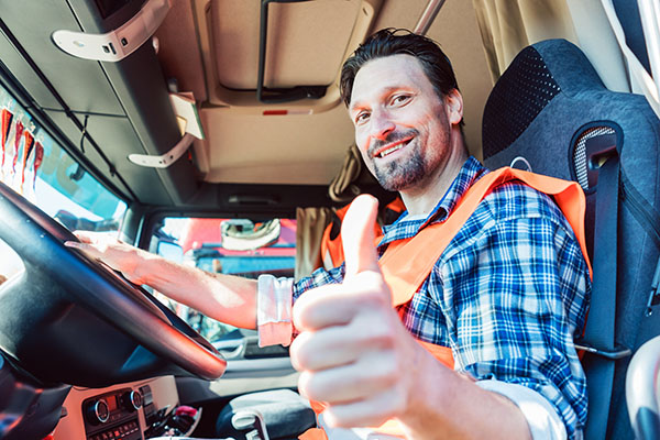 Truck driver sitting in cabin giving thumbs-up